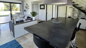 A modern kitchen with a large island, a dining area with a sofa, and a staircase leading to an upper level. - Haven of peace in the vineyards (Violes)