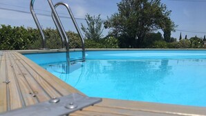 Une terrasse en bois entourant une piscine, avec des rampes en métal et une eau d’un bleu limpide.