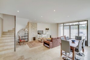 A modern living room with a staircase, a sofa, a dining table with chairs, and a TV. - MAS DE JONQUERETTES with swimming pool (Jonquerettes)