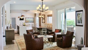 A spacious living area with leather sofas, a dining table, and a chandelier. - Luxury  Villa with heated pool, spa/hot tub, dock, near beach,  Sunsets! (St. Augustine)