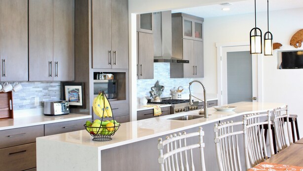 A modern kitchen with grey cabinets, a central island with a fruit bowl, and a stainless steel sink. - Luxury  Villa with heated pool, spa/hot tub, dock, near beach,  Sunsets! (St. Augustine)