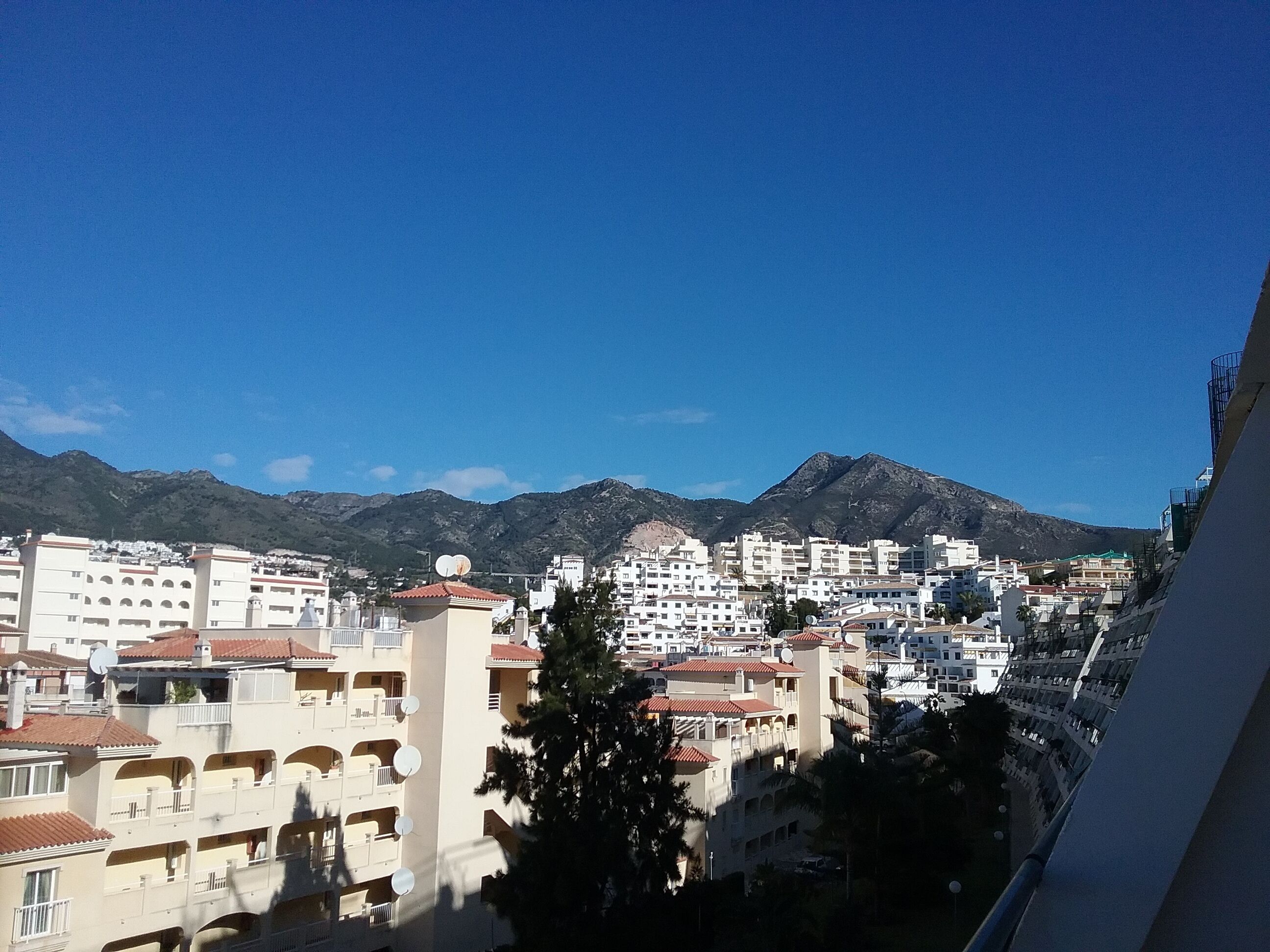 Une vue urbaine avec des bâtiments et des montagnes en arrière-plan.
