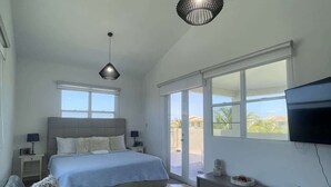 A bedroom with a bed, a TV, a sofa, and a balcony with a view.
