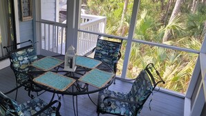 Een overdekt terras met een ronde tafel en vier stoelen, omringd door een witte balustrade.