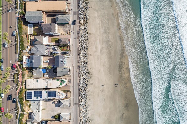 Una vista aerea di una zona residenziale sulla costa, con case, una strada e una spiaggia.