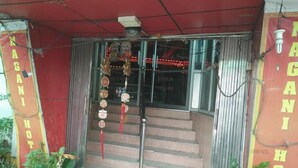 A building entrance with a staircase, a metal railing, and decorative hanging ornaments.