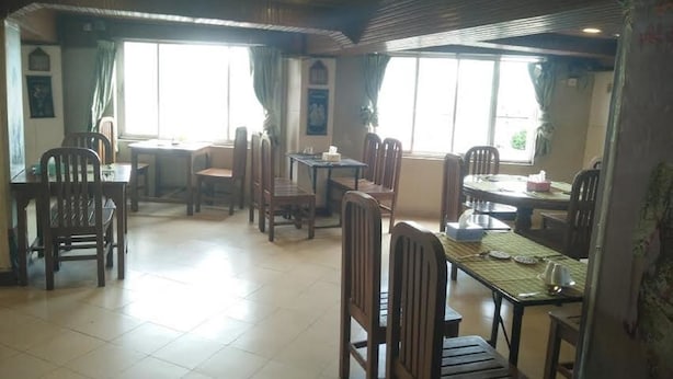 A dining area with multiple tables and chairs, large windows, and a tiled floor.
