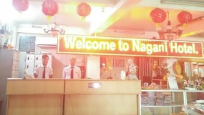 A reception desk with a 'Welcome to Nagani Hotel' sign, reception staff, and a counter with various items.