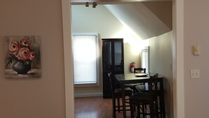 A dining area with a table and chairs, a painting on the wall, and a window with blinds. - Right in the Quaint Village of Hammondsport (Hammondsport)