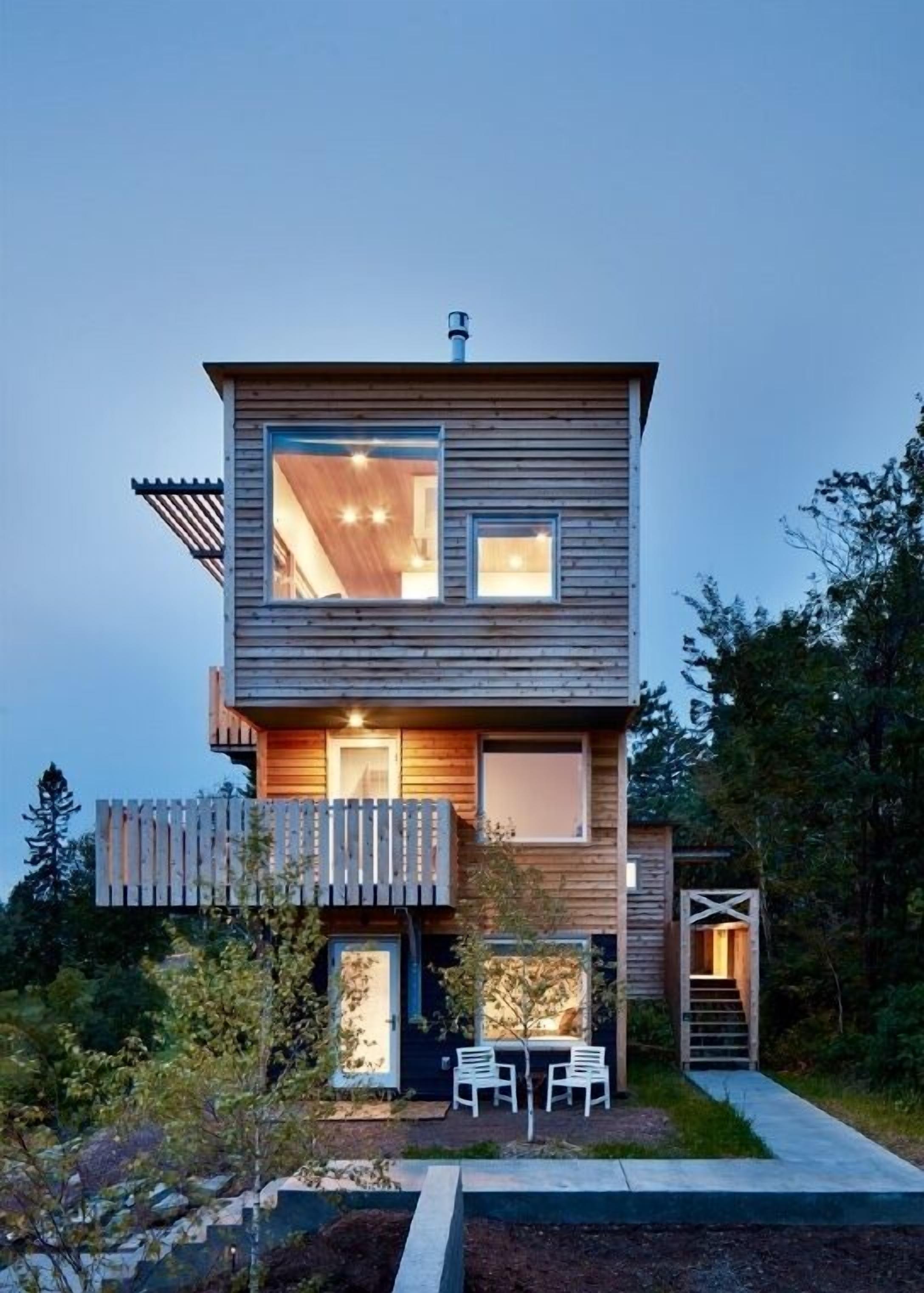 Une maison moderne à deux étages, construite en bois, dotée d’une terrasse et d’un espace salon extérieur.