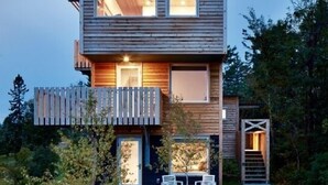 A modern two-story wooden house with a deck and outdoor seating. - The SkyHouse- Life as Art- Sauna Available (Grand Marais)