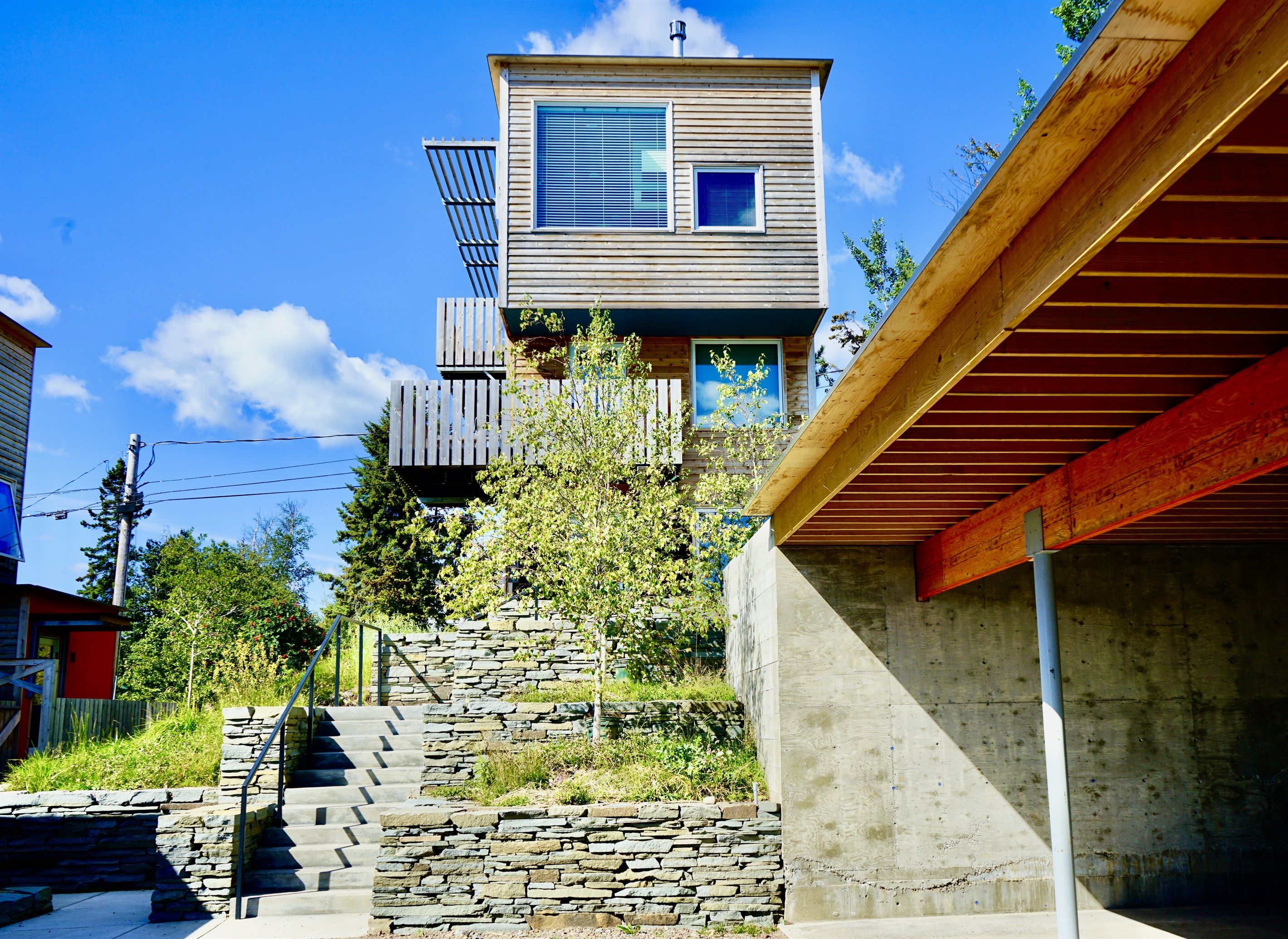 A modern two-story house with a stone staircase leading to the entrance.
