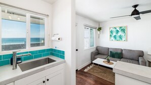 A modern kitchen with a large window, a built-in sink, and a teal backsplash.