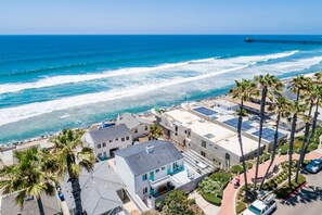 A coastal hotel with a view of the ocean, palm trees, and a pier in the background. - 🐬 Stroll to the Beach from Pacific Villas #5 (Oceanside)