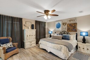 A bedroom with a bed, two bedside tables with lamps, a ceiling fan, a dresser, and a chair. - Updated Home-Priv Hot Tub-Comm Pool-Close 2 Beach (Destin)
