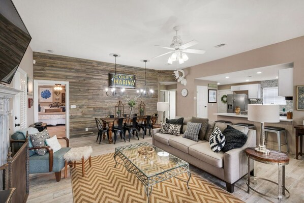 A modern living room with a herringbone-patterned rug, a glass coffee table, and a sofa with patterned cushions.