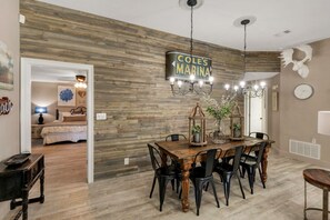 A dining area with a wooden wall, a chandelier, and a sign reading "COLES MARINA".