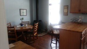A kitchen with wooden cabinets, a round dining table, chairs, a potted plant, and a toaster.