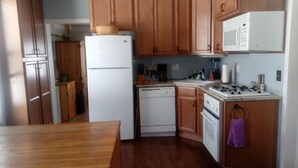 A kitchen with wooden cabinets, a white refrigerator, a dishwasher, a stove, and a microwave.