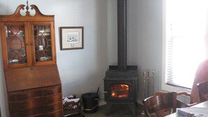 A room with a wooden cabinet, a fireplace, a rug, and a dining table.