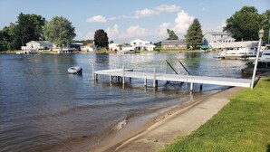 A waterfront dock with a concrete walkway leading to a grassy area.