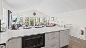 Una cocina amplia con una isla grande, armarios blancos y un microondas moderno.