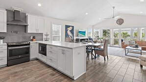 Una cocina moderna con armarios blancos, una isla grande y un comedor con vistas.