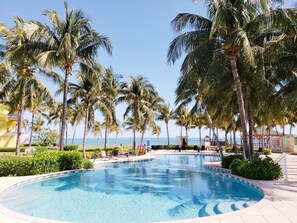 Una piscina circondata da palme, con vista sull'oceano sullo sfondo.