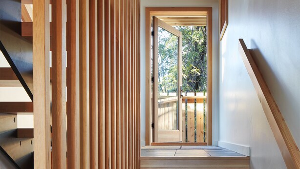 A wooden staircase with a view of a garden through a glass door. - The Aurora- Award Winning- Sauna available (Grand Marais)
