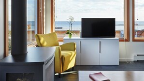 A modern living room with a fireplace, a sofa, a television, and a view of the sea. - The Aurora- Award Winning- Sauna available (Grand Marais)