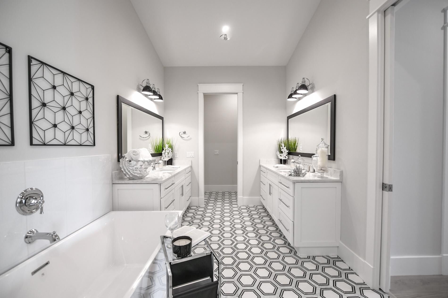 Un baño moderno con piso de diseño geométrico, dos lavamanos con espejos, una bañera y plantas decorativas.