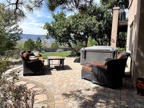 An outdoor patio with wicker furniture, a barbecue grill, and a view of the landscape.
