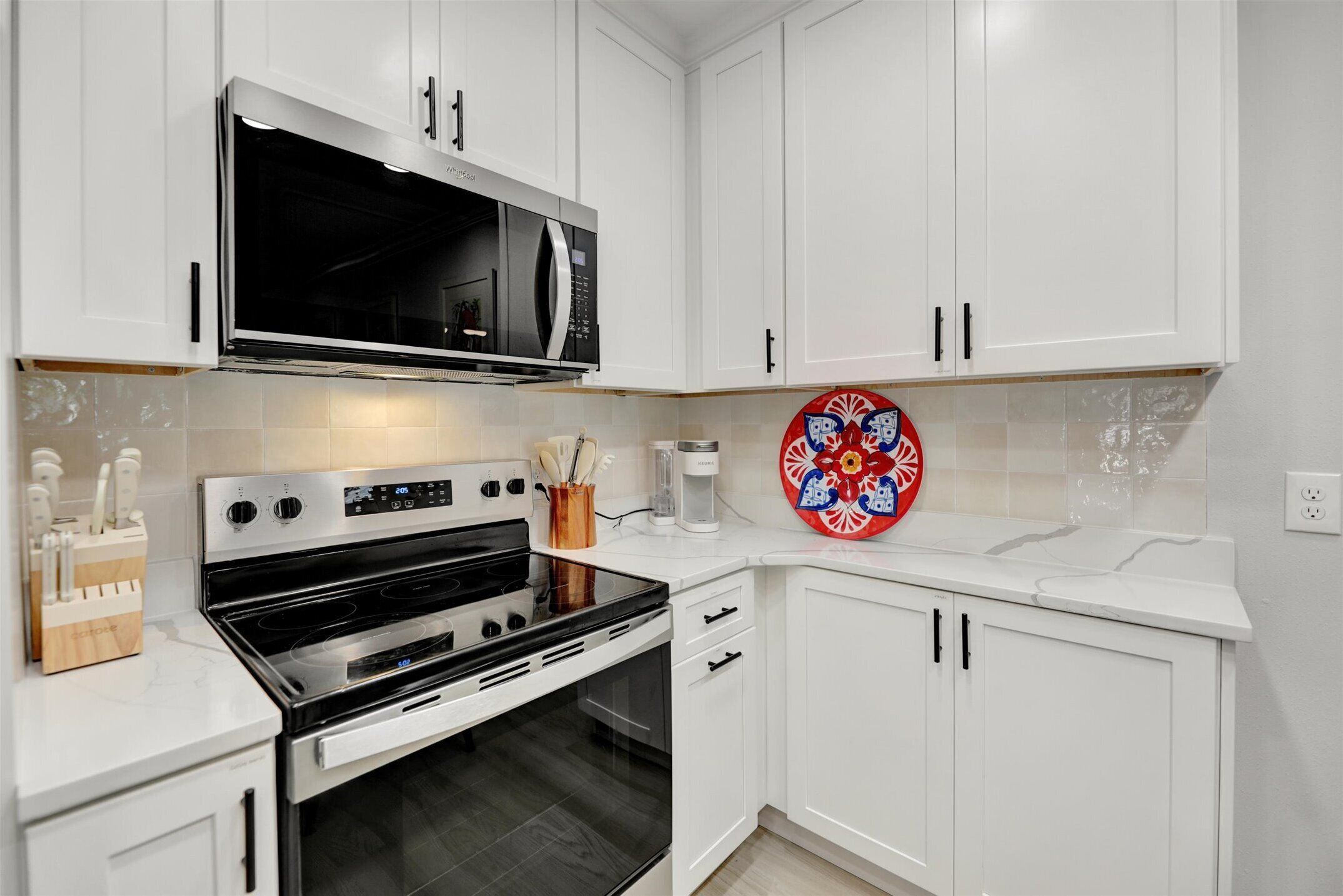 A modern kitchen with white cabinets, a stainless steel stove, and a microwave.