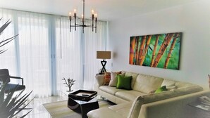 A modern living room with a sofa, a coffee table, a lamp, and a painting on the wall. - GORGEOUS 2BD/2 BATH ON THE BEACH! DESIGNER APT.LUX! BEST LOCATION. (Cangrejo Arriba)