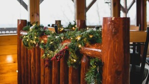 Une rambarde en bois ornée de verdure et de guirlandes lumineuses, probablement dans un décor de style rustique ou évoquant un chalet.