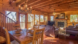 L'intérieur d'un chalet en bois comprend un coin repas, un salon et une cheminée.
