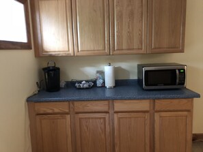 Kitchen area with coffee maker, microwave, and tea station.