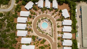 An aerial view of a resort with a central swimming pool, arranged villas, and a winding road. - Pelican House | Walk to Beach + Pool Access in Seagrove (Santa Rosa Beach)