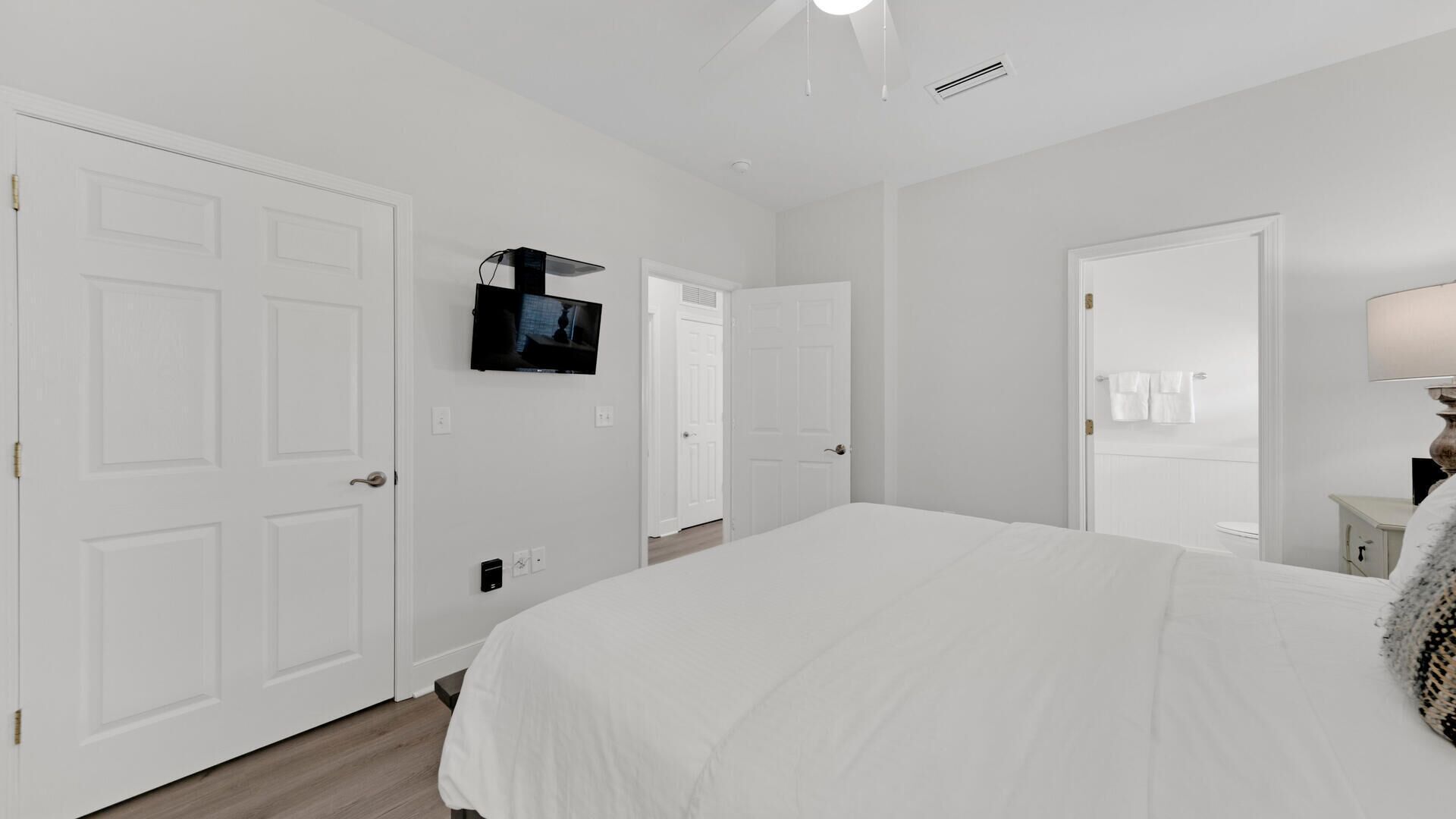 Una camera da letto con un letto grande, una televisione montata a parete e porte bianche.