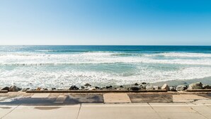 Une promenade en bord de mer offrant une vue sur l’océan, protégée par une barrière en pierre.