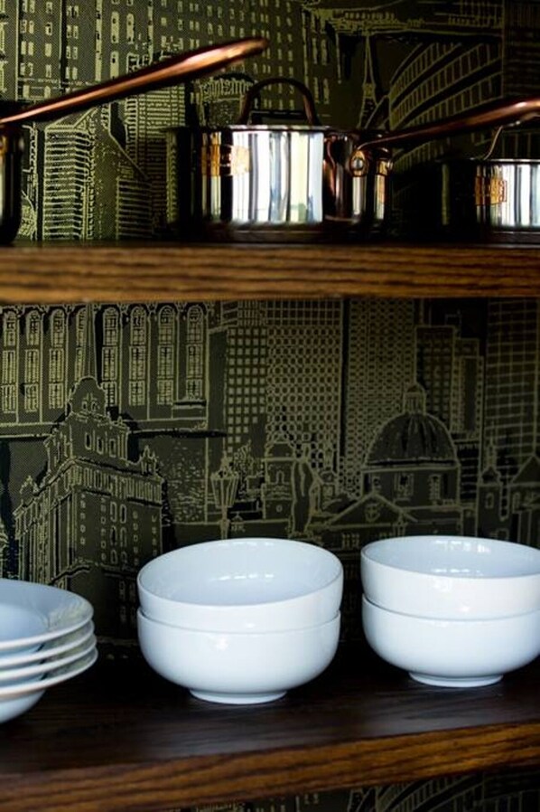 A set of white bowls on a wooden shelf with a cityscape wallpaper background.