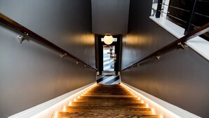 Un escalier en bois au design moderne, menant à une porte.