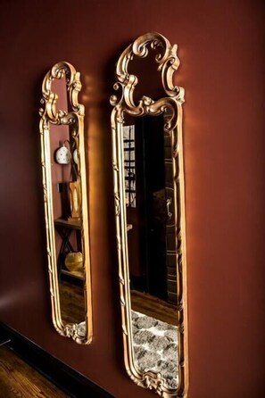 Two ornate mirrors with gold frames mounted on a dark wall.
