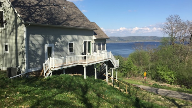 Una casa a due piani con un terrazzo che si affaccia su un lago.