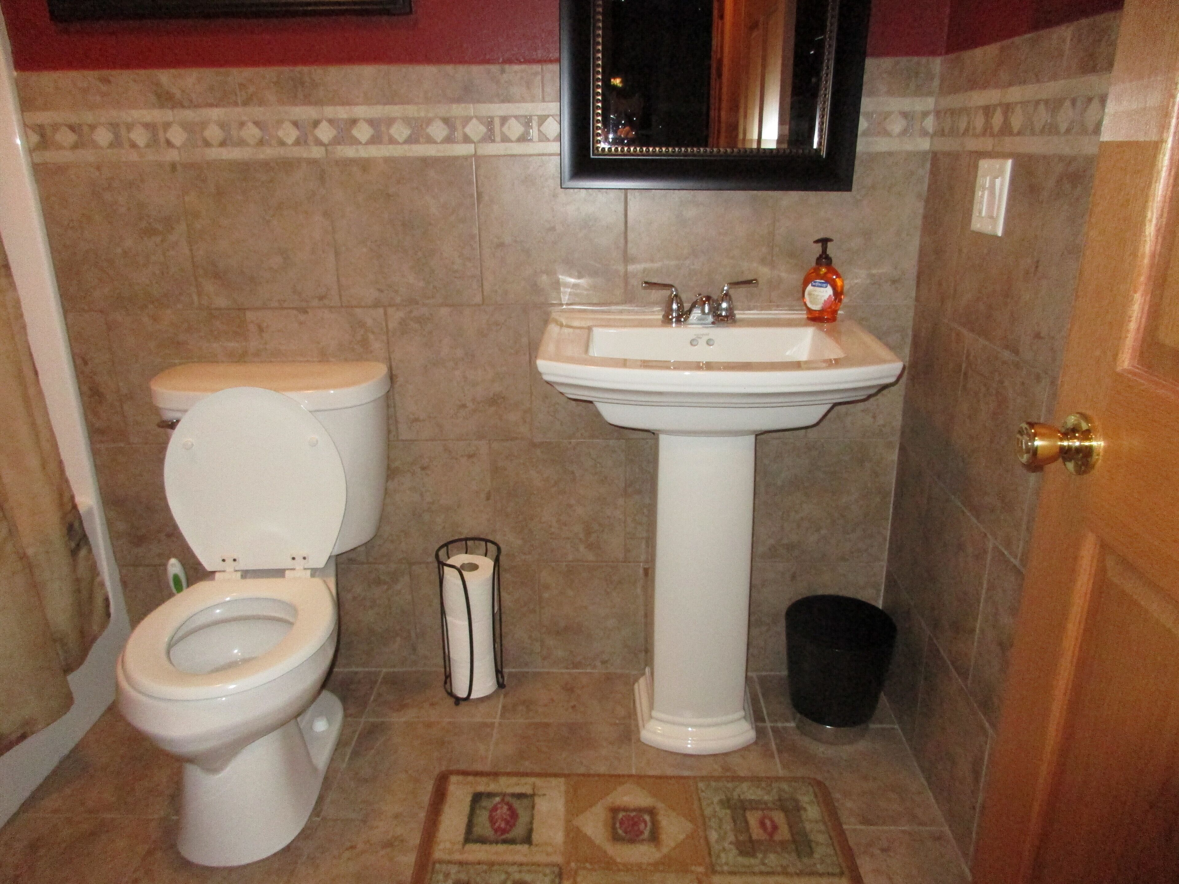 A bathroom with a toilet, sink, and a trash bin.