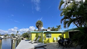 A dock with a small yellow building, lounge chairs, and a palm tree. - Sun, beach, and unbeatable prices! (Matlacha)
