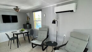 A modern living room with a dining area, grey walls, and a flat-screen TV. - Sun, beach, and unbeatable prices! (Matlacha)