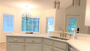 A kitchen with a large island, double sinks, and a chandelier. - Bannister Cottage – Lakefront Getaway w/ Dock, Porch & Views, 20 mins to Clemson (Anderson)