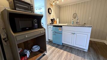 Une cuisine compacte équipée d’un four à micro-ondes, d’une machine à café et d’un petit réfrigérateur.