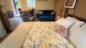 Une chambre d’hôtel avec un lit, un canapé, une chaise, une table et un tableau au mur.